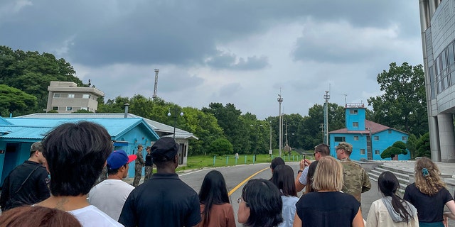 Tourists stand near a border station at Panmunjom in the DMZ between South and North Korea