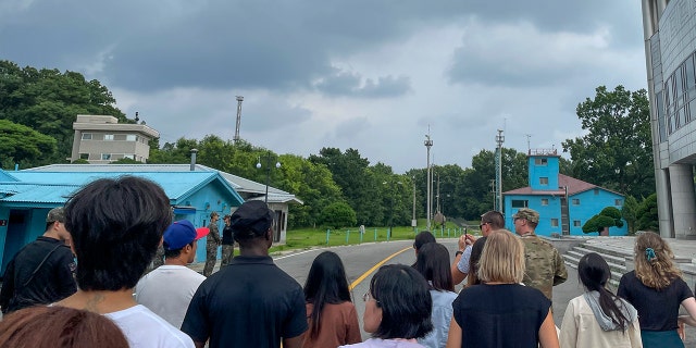 Tourists stand near a border station at Panmunjom in the DMZ between South and North Korea