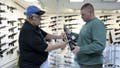 Roger Krahl, president of RGuns, left, gives information to Zack Johnson about an RGuns-brand TRR15 model rifle at Krahl's gun store in Carpentersville, Illinois. A Democrat bill would impose a 1,000% excise tax on semiautomatic weapons and high-capacity magazines. (John J. Kim/Chicago Tribune/Tribune News Service via Getty Images)