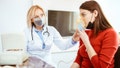 Female doctor applying medicine inhalation treatment on a young woman in doctor's office. Hard breathing due to asthma or allergies.