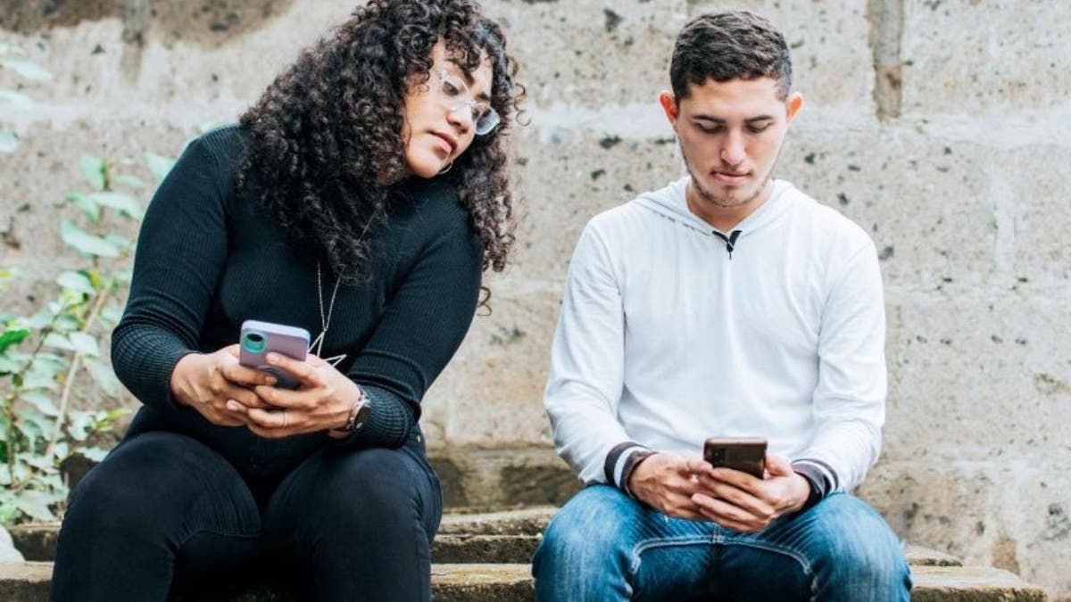 Woman looking at a man's phone while he's on it.