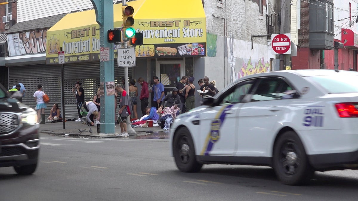 Police car drives past drug users in Kensington