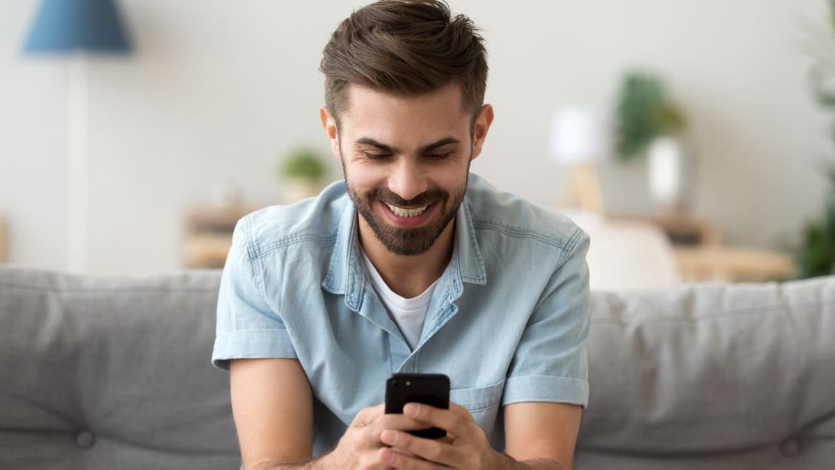 Man smiles as he works on his phone