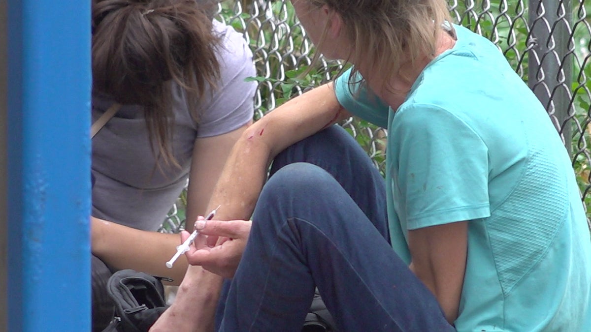 A drug user injecting herself with a needle