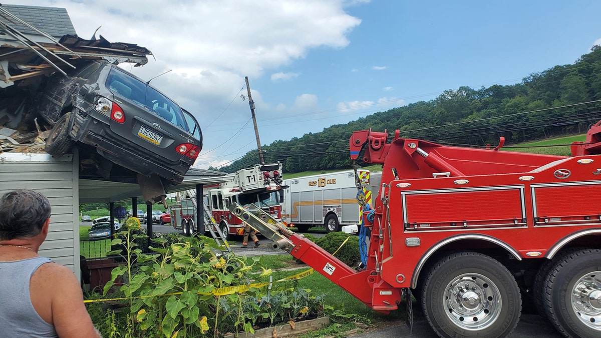 Car being towed from second floor roof area of home