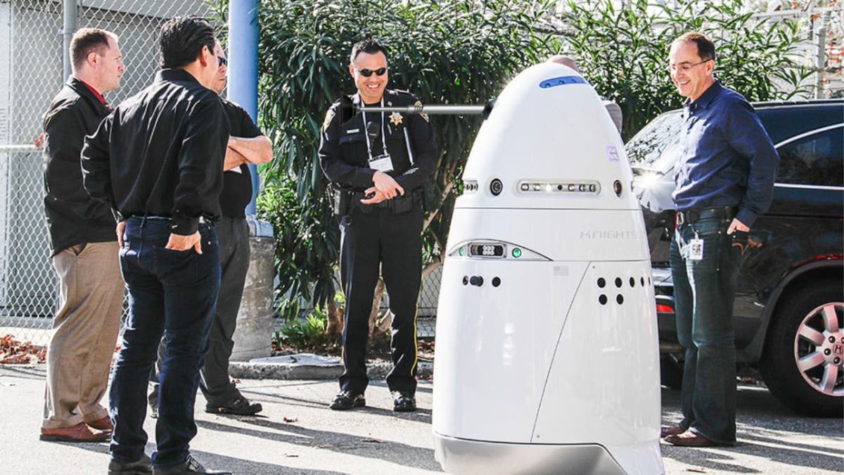 Photo of police officers and a robot security guard.
