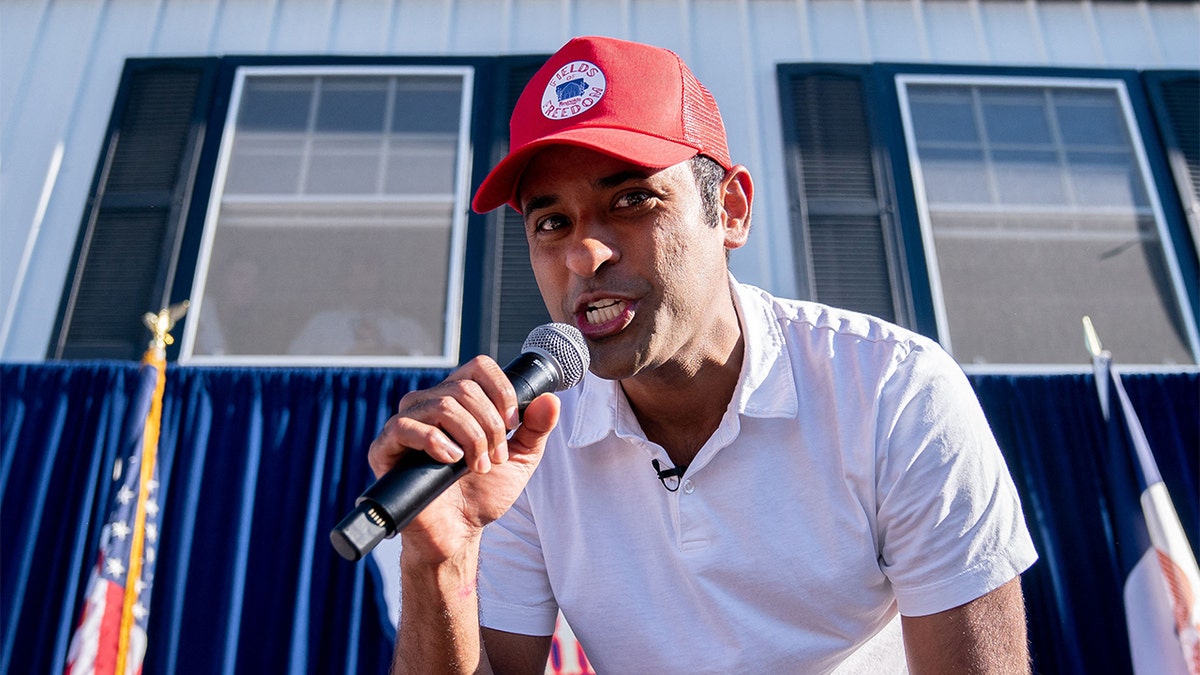 GOP presidential hopeful Vivek Ramaswamy in red cap, white shirt holding microphone