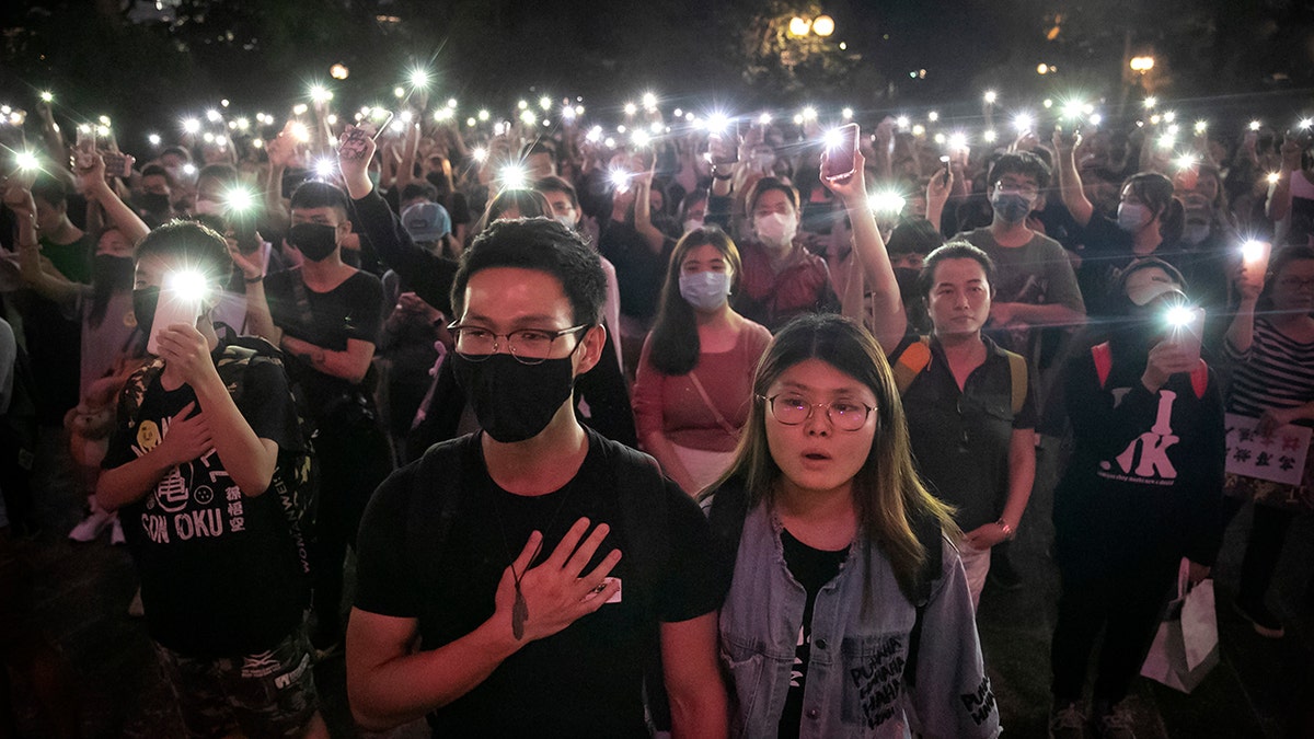 Demonstrators hold their cellphones 