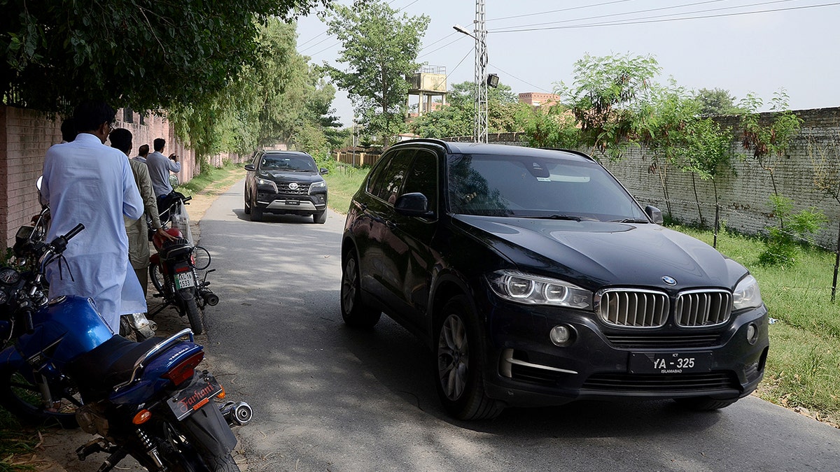 Police officers stop a vehicle carrying Bushra Bibi