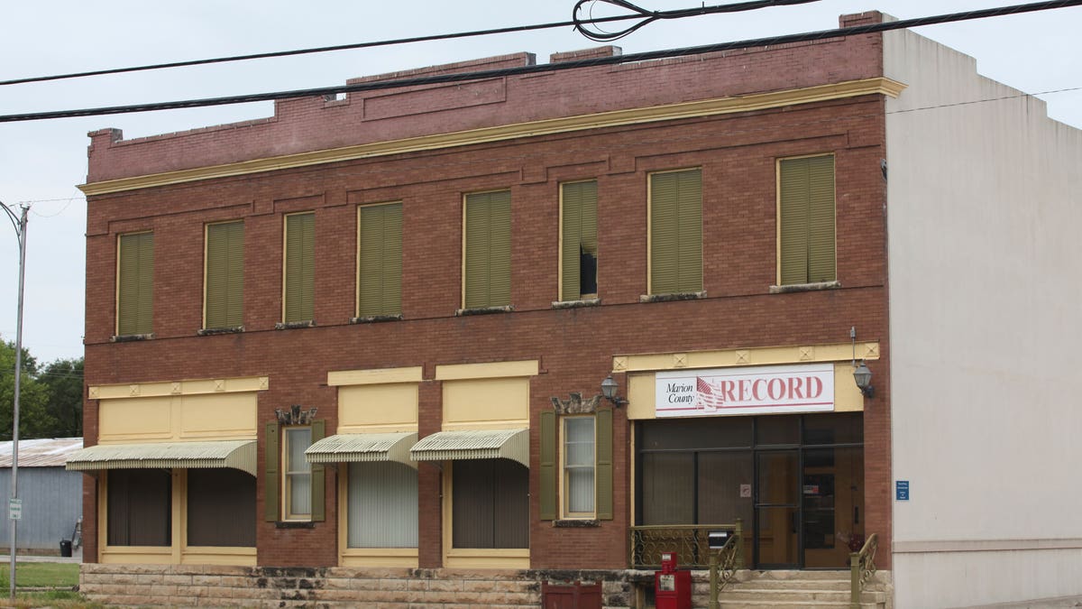 The Marion County Record headquarters, a two-story brick building with blinds and curtains closed