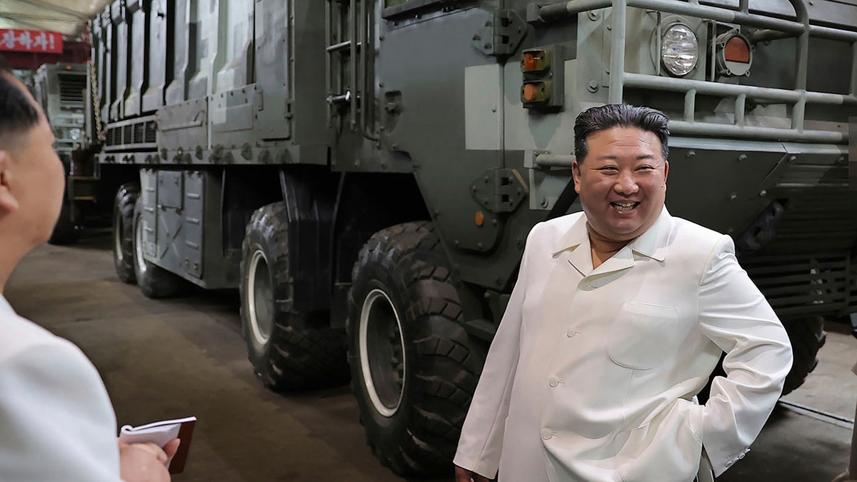 Kim near a heavily armored vehicle