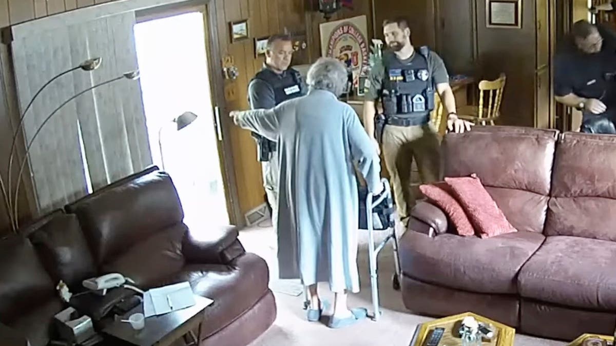Joan Meyer gestures at officers in her living room, ordering them to get out of her house