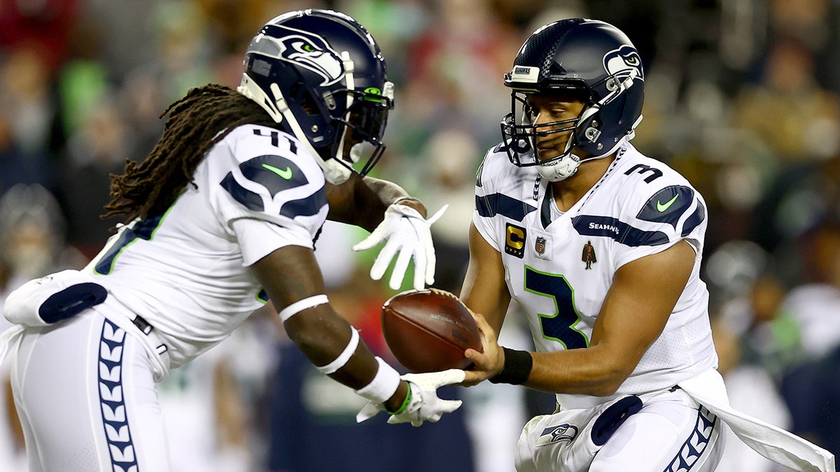 Russell Wilson hands the ball off to Alex Collins