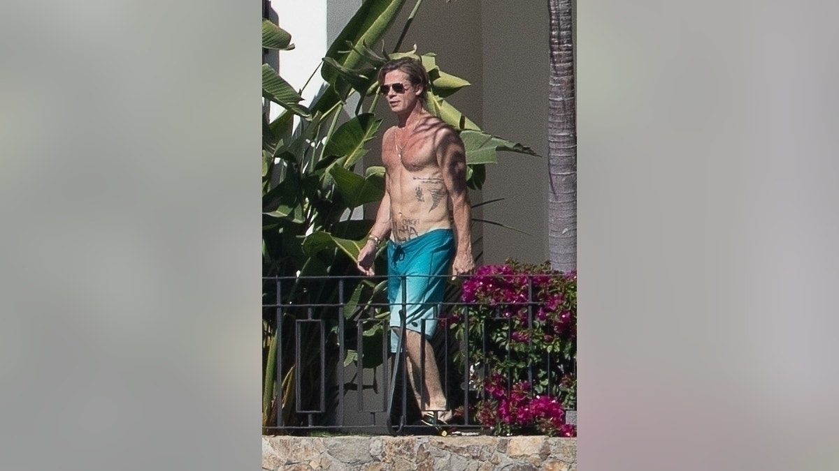 brad pitt walking shirtless in blue swimsuit in cabo