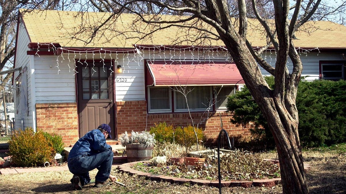 Man crouching in front of the house