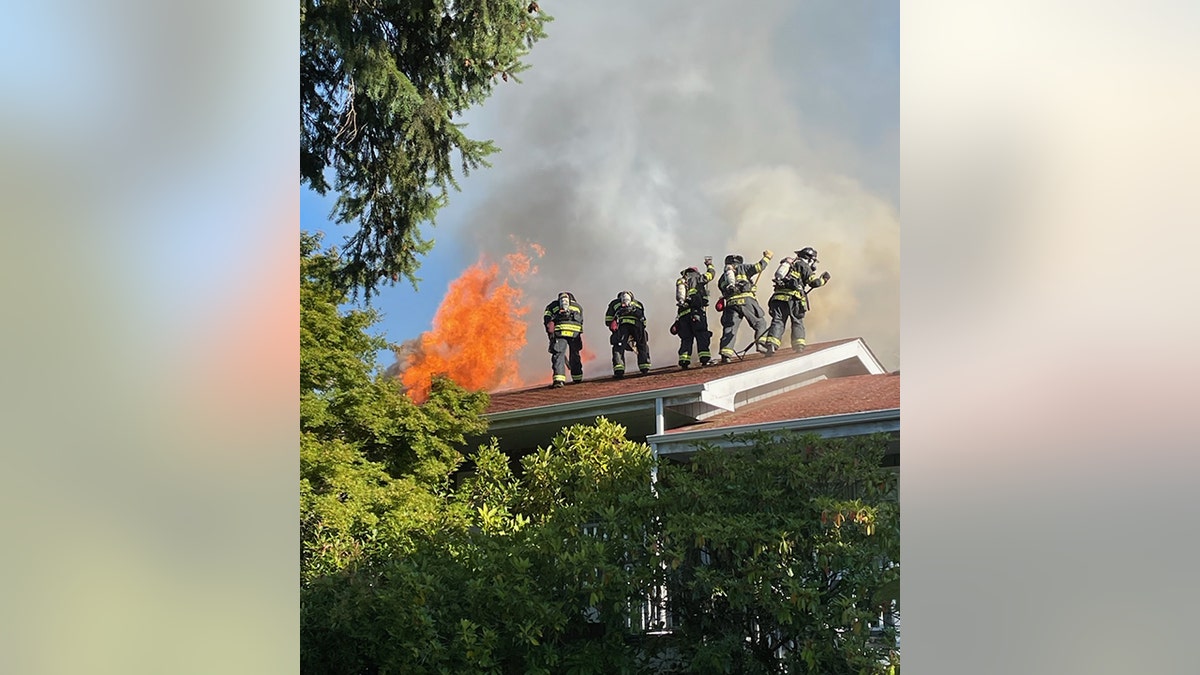 firefighters on roof of building with flames