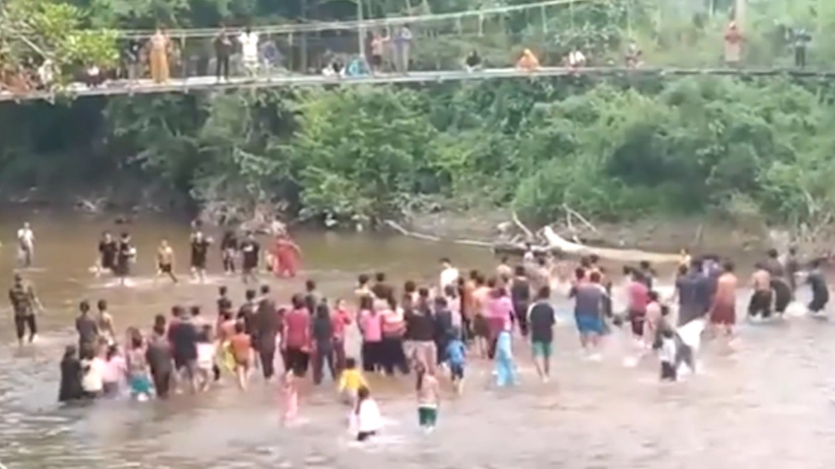 People on a bridge and in the water in Indonesia