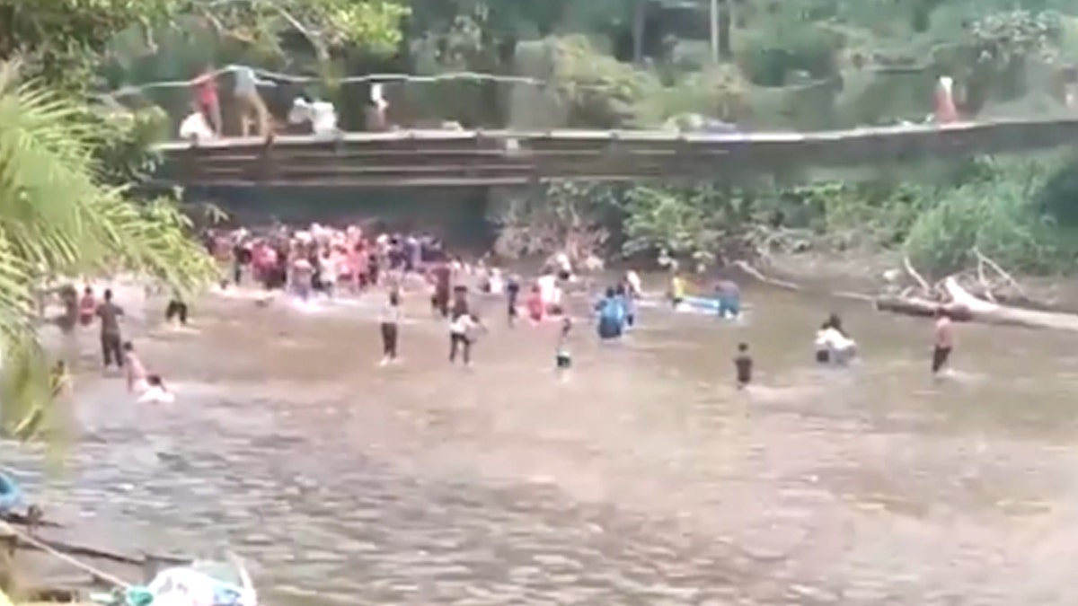 A bridge with people starts to collapse above people in the water in Indonesia