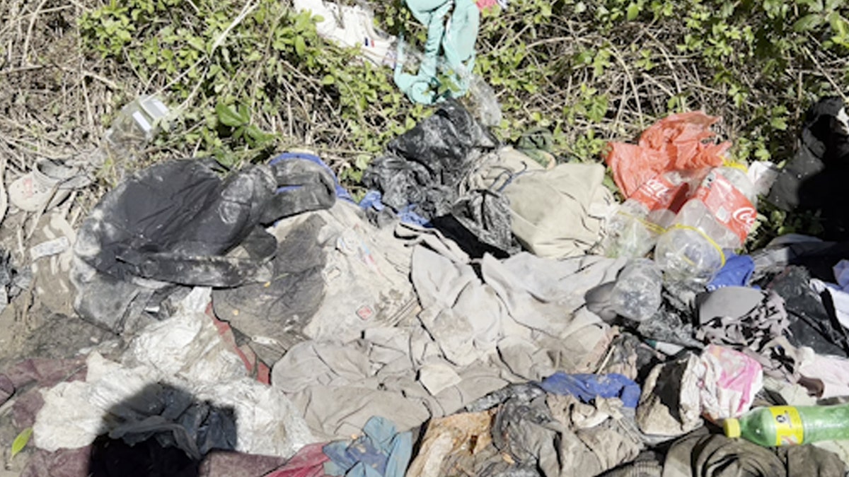 Piles of clothes and trash on the riverbank near U.S. border