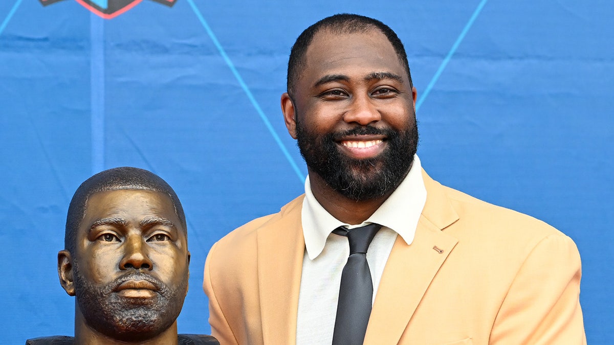 Darrelle Revis smiles next to bust
