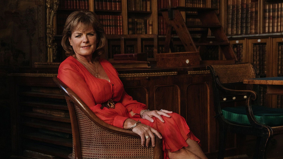 Emma, Duchess of Rutland wearing a red dress and sitting on a couch