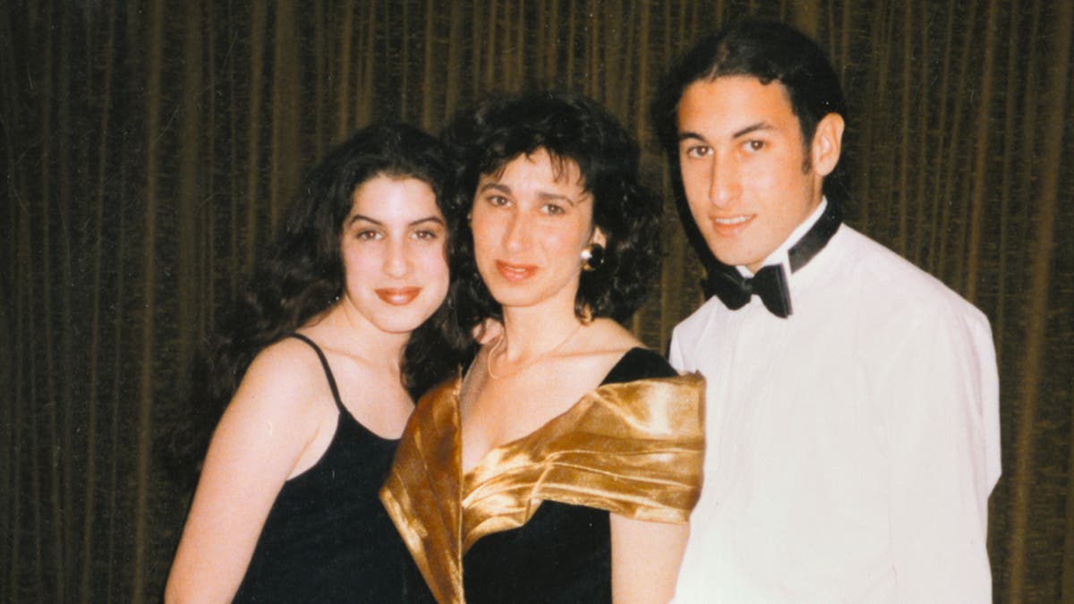 Amy Winehouse with a black tank top posing with her mother Janis and Mitch in formal wear