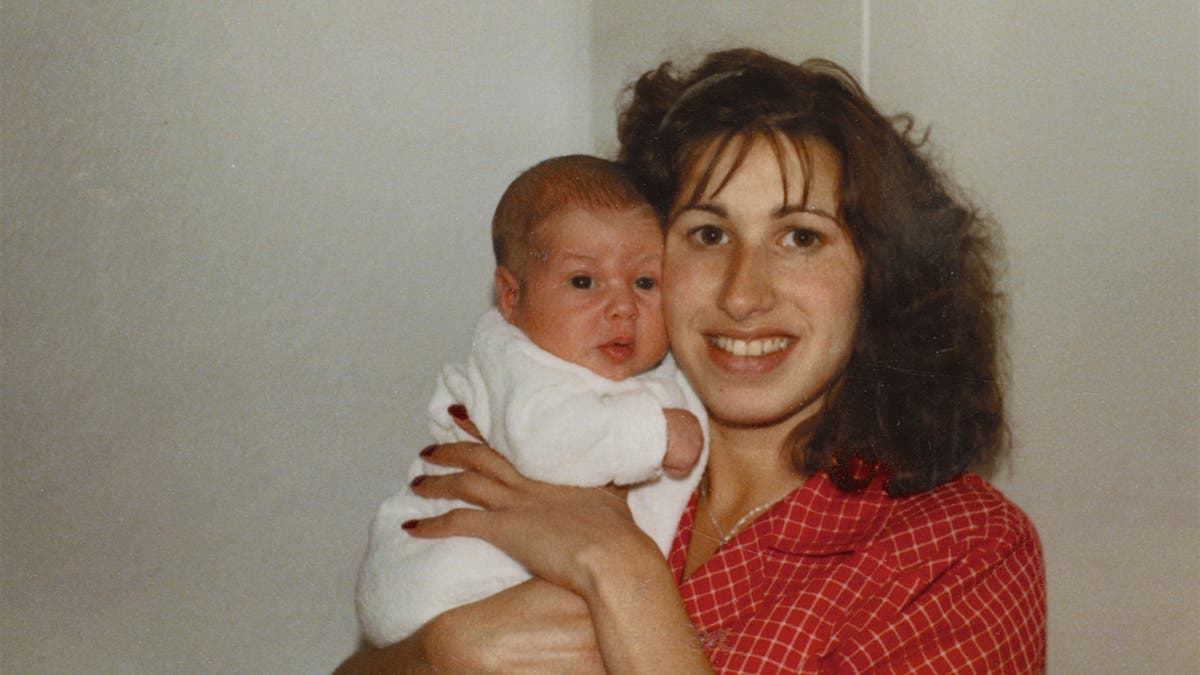 Janis wearing a red printed blouse holding on to a baby Amy Winehouse