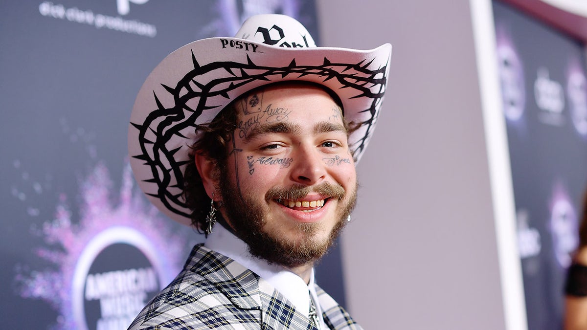 Rapper Post Malone wears a pink cowboy hat and matching suit.