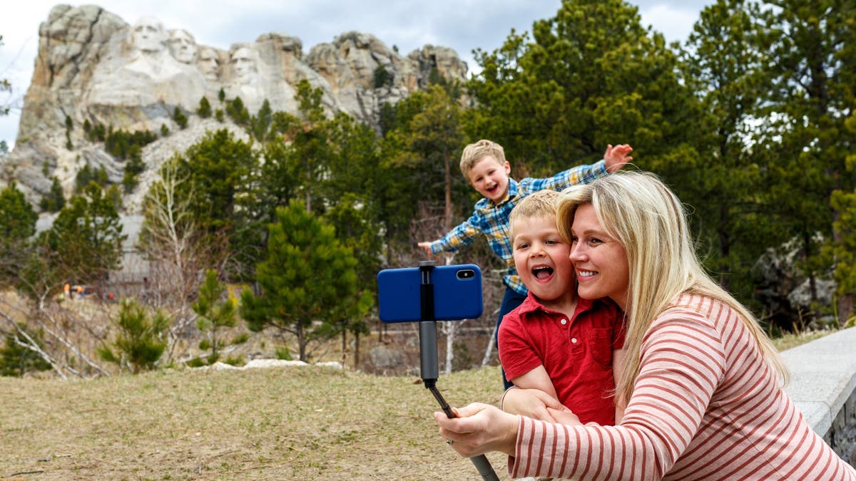 A mother poses for a selfie with her two sons with Mt. Rushmore in the background