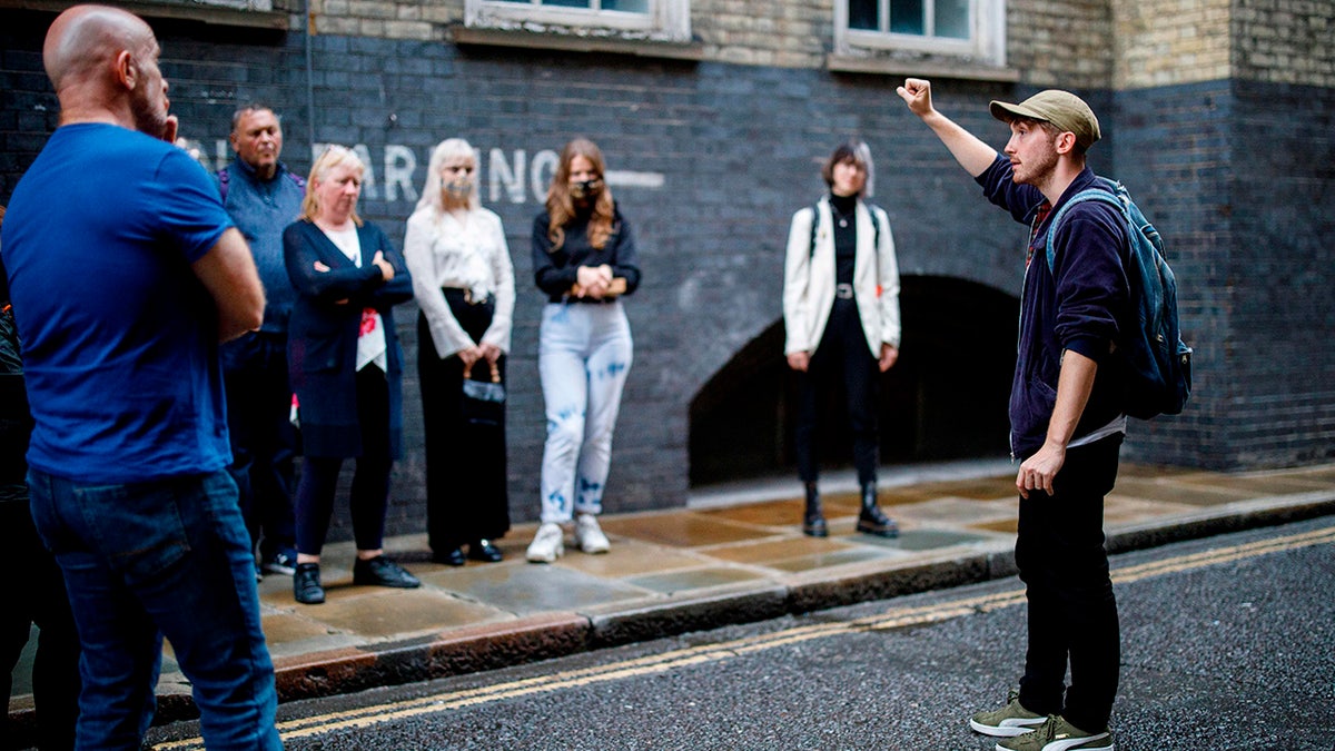 Tour guide Joel Robinson, right, leads a group of visitors and tourists on a Jack the Ripper tour in London on Aug. 24, 2020. More than a century after the murders, the crimes still fascinate many people. 