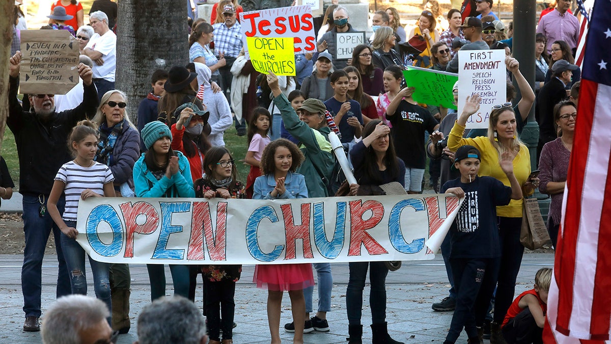 Protesters hold an "open church" sign in support of Calvary Chapel San Jose