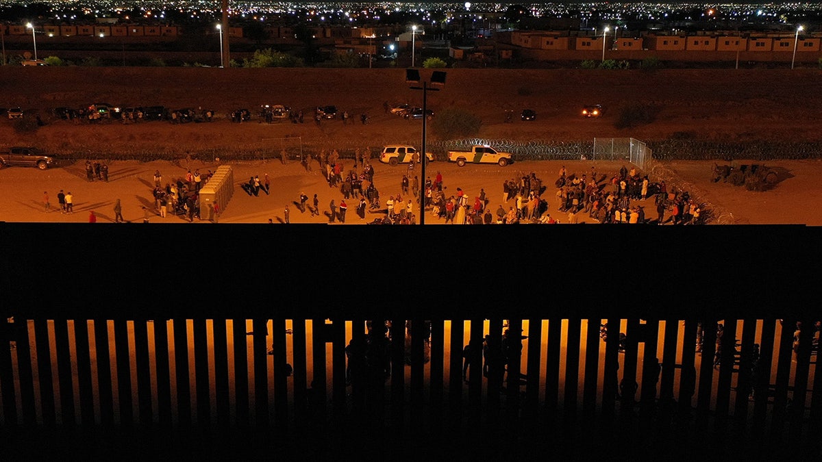 Crowds of migrants by Texas border wall