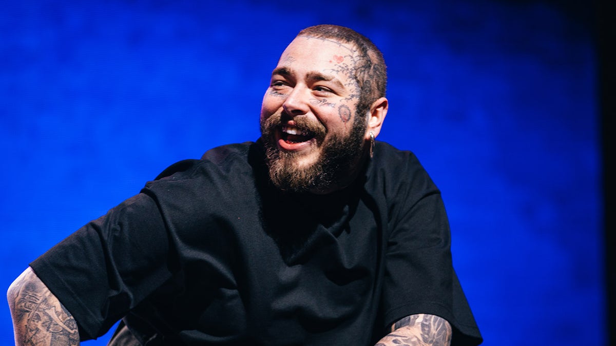 Post Malone laughing on stage at Coachella in a black shirt