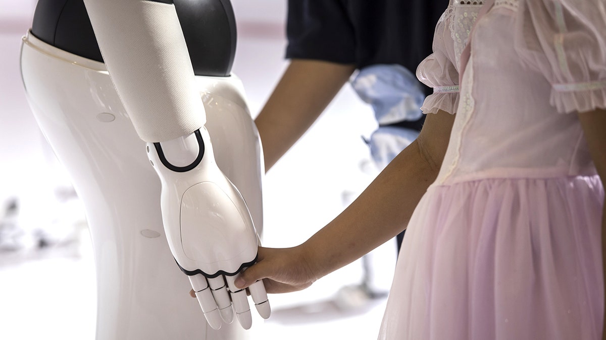 child holds robot's hand