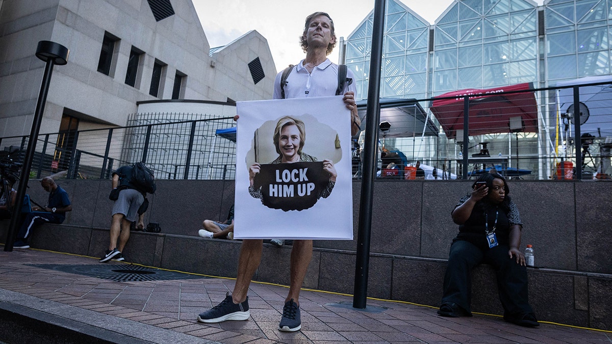A demonstrator holds a "Lock Him Up" anti-Trump sign outside of the Lewis R. Slaton Courthouse ahead of an expected indictment of former US President Donald Trump on August 14, 2023, in Atlanta, Georgia.