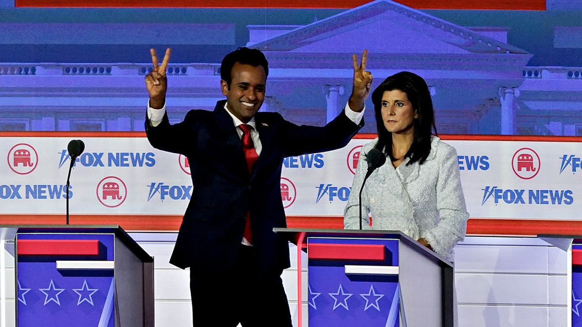 Ramaswamy puts up the peace sign to the audience next to Haley on the debate stage