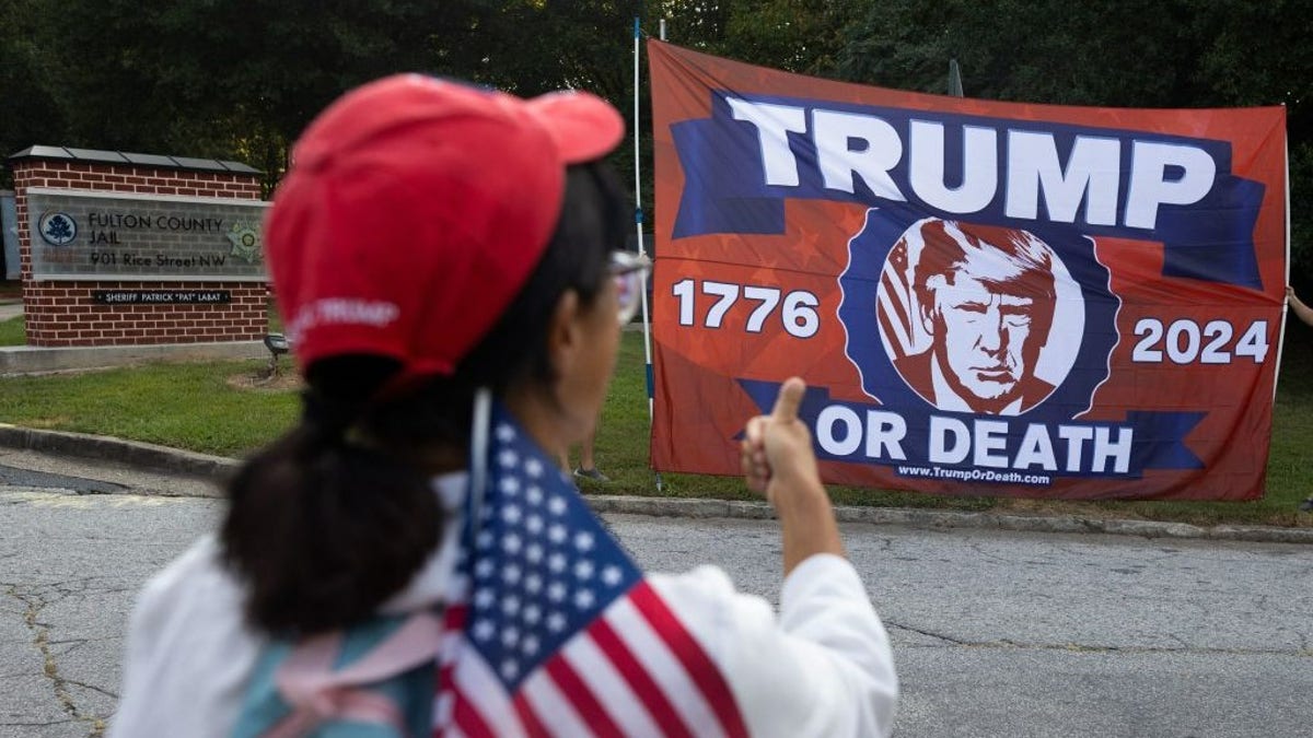 Trump supporter in Georgia in foreground, Trump banner in background