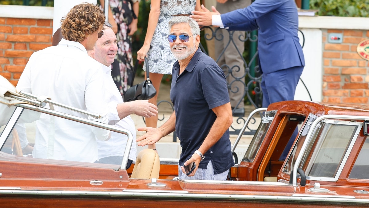 george clooney smiling on boat in venice