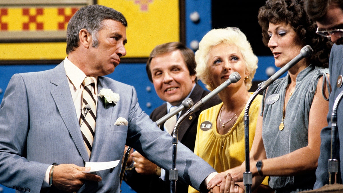 Richard Dawson holds hands with a contestant on Family Feud
