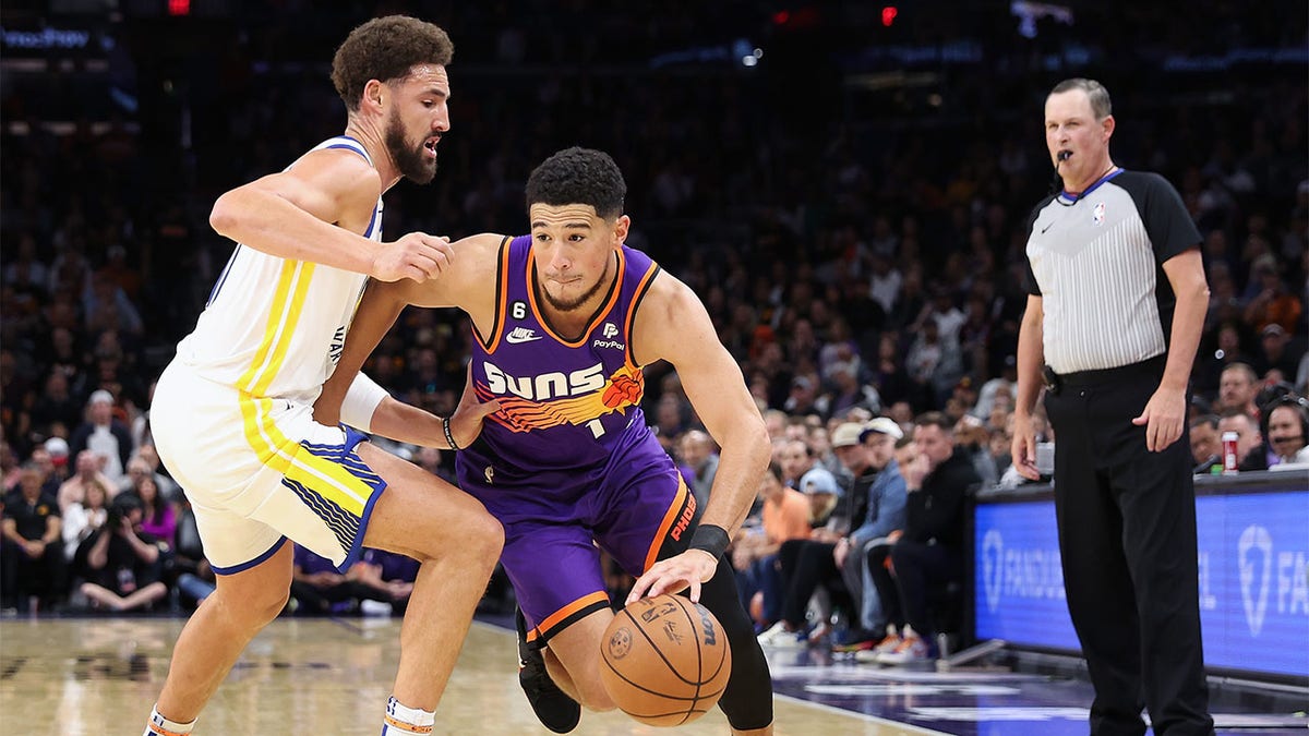 Devin Booker drives against Klay Thompson