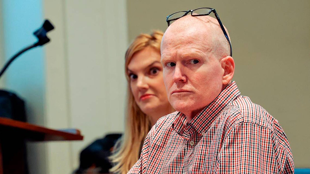 a close-up of the bald Alex Murdaugh in sitting in court with a plaid shirt next to his legal team