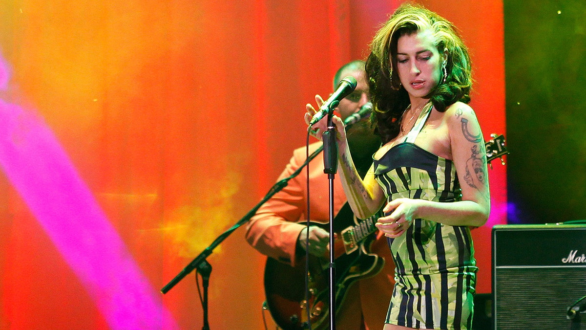 Amy Winehouse in a striped dress on stage