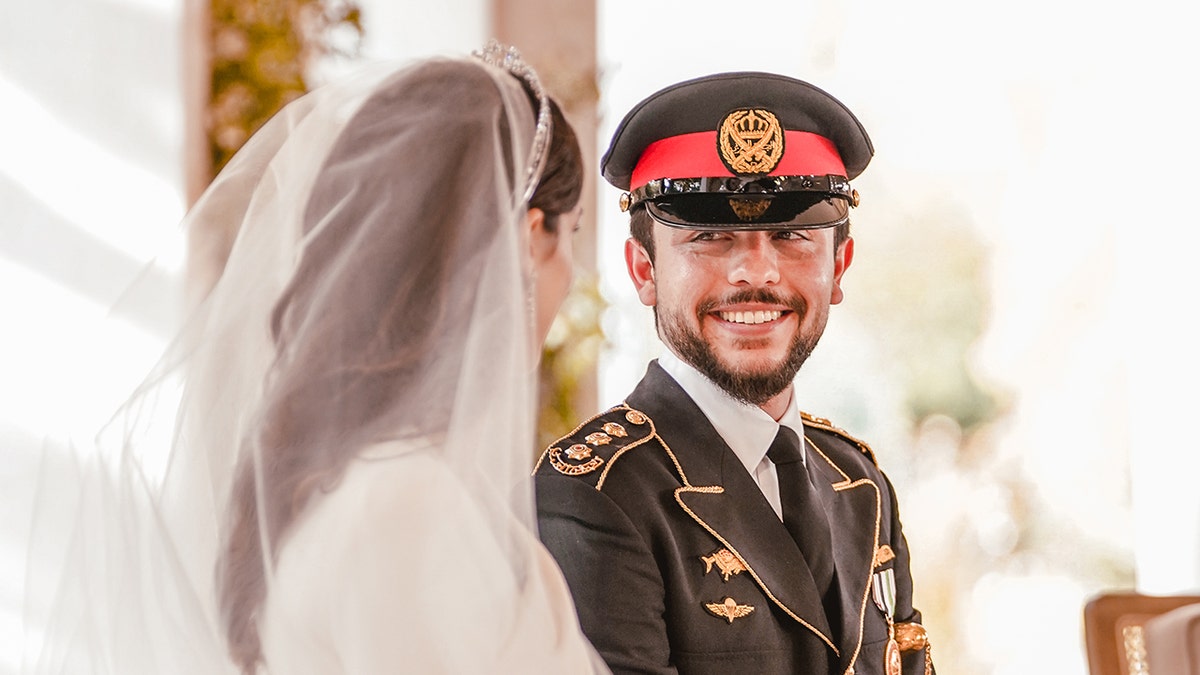 Crown Prince Hussein in his military uniform admiring his bride