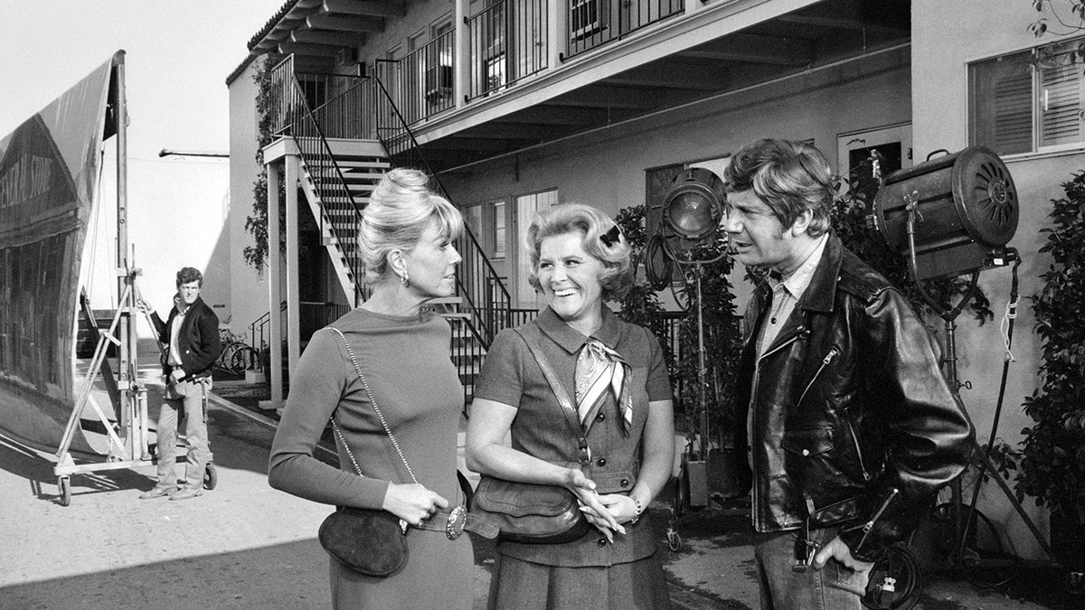 Doris Day and Rose Marie walking together on set as they smile at each other
