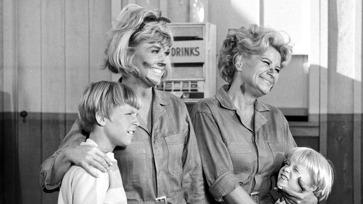 Doris Day and Rose Marie wearing dirty jumpsuits as they embrace two child actors