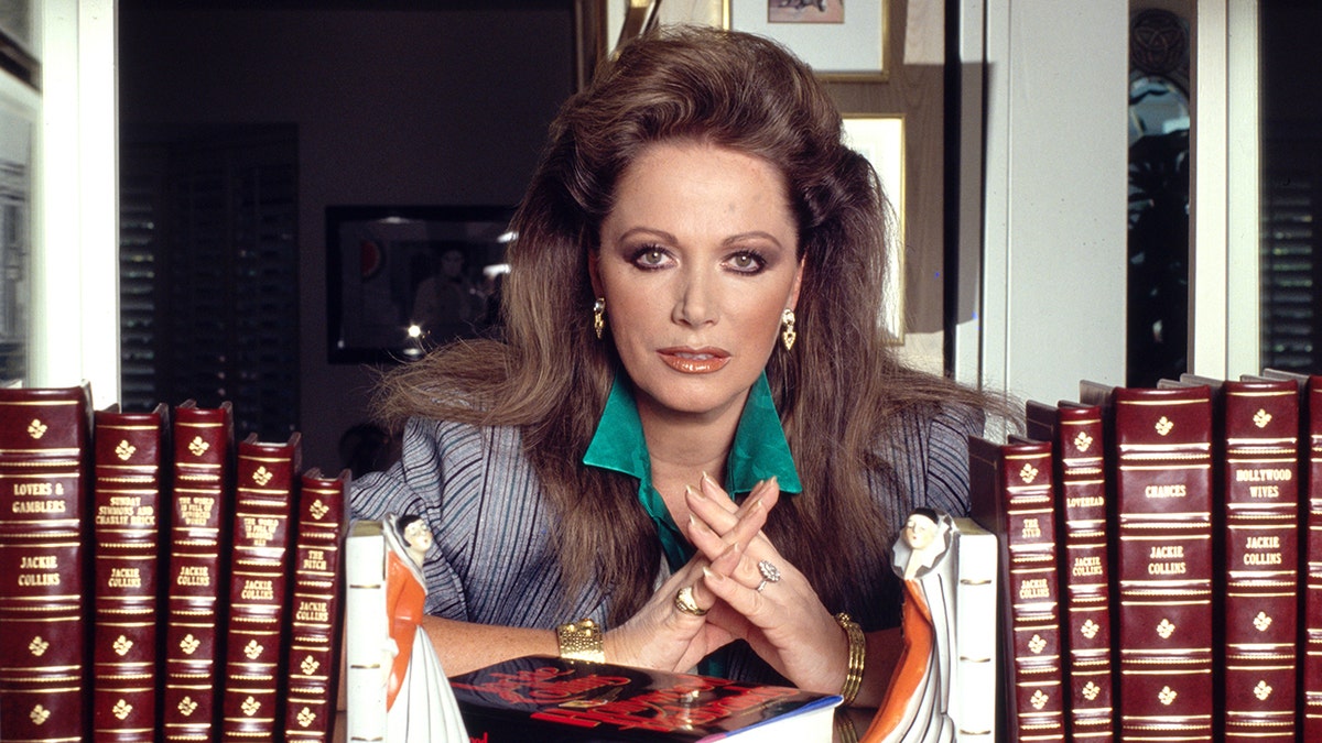 Jackie Collins posing with all the books shes written
