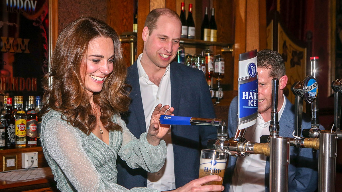 Kate Middleton wearing a pale green dress working the bar as prince william watches