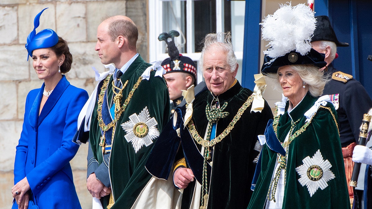 Kate Middleton in a cobalt blue dress and matching hat standing next to Prince William, King Charles and Queen Camilla as they wear formal royal wear