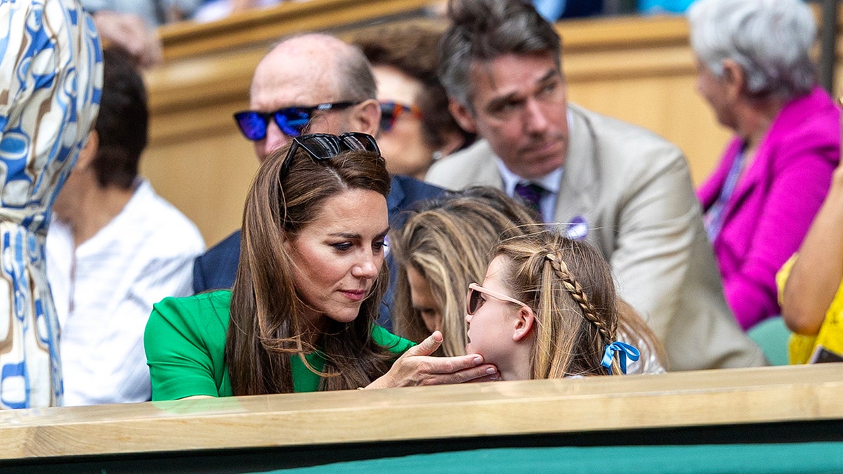 Kate Middleton in a bright green dress caressing her daughters face