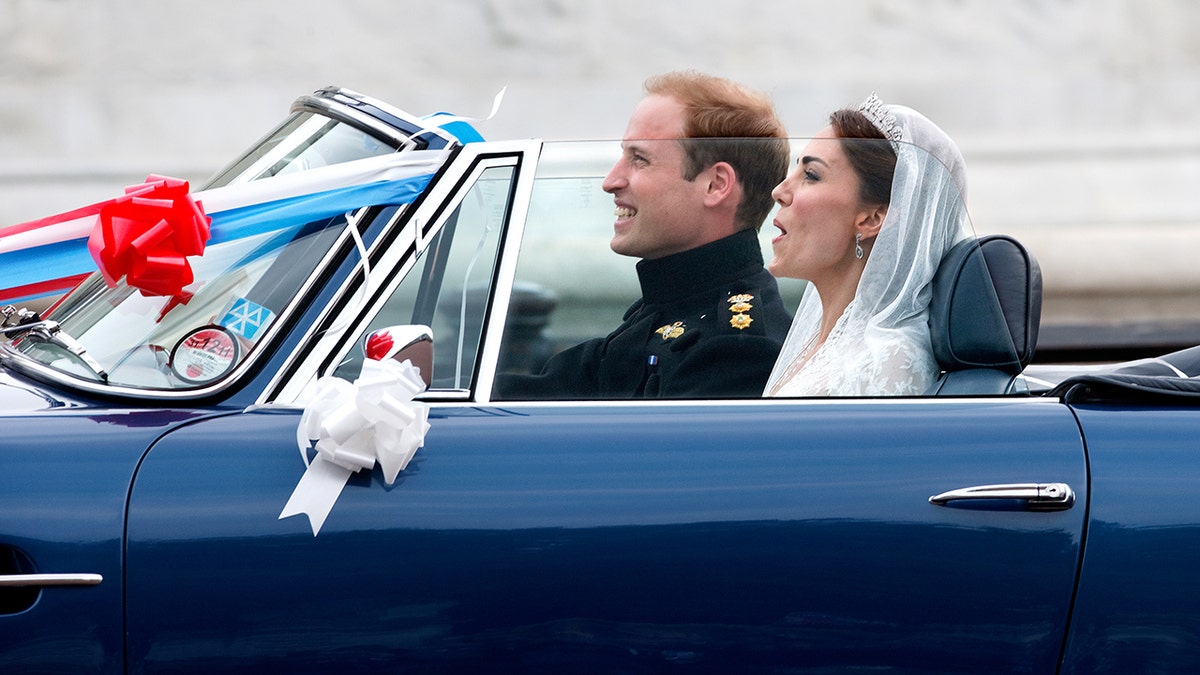 Kate Middleton in a bridal gown sitting in a car next to Prince William on their wedding day